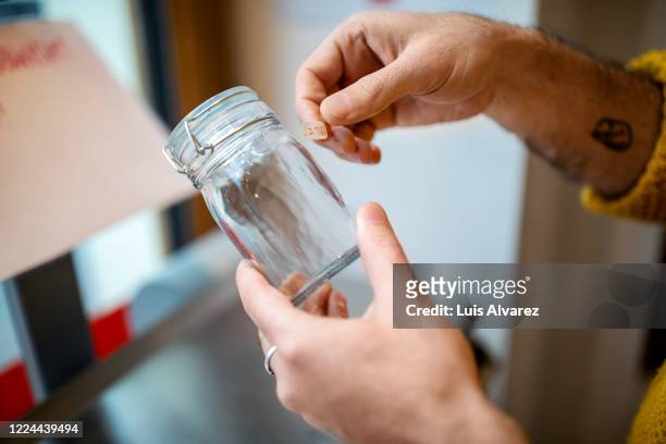 hands of male customer labeling glass jar at zero waste store - labeling stockfoto's en -beelden