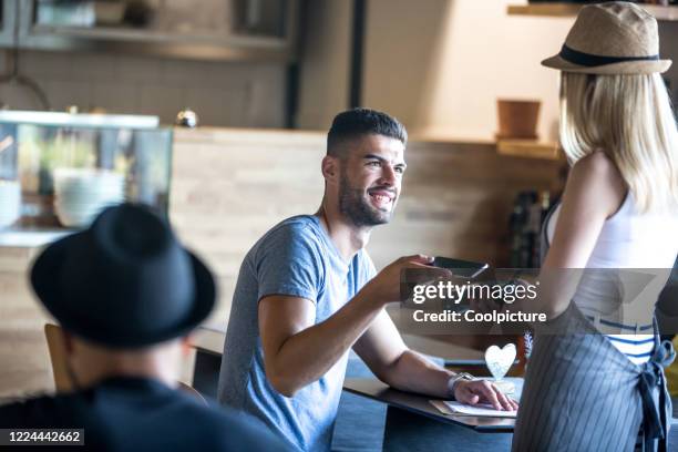 waiter with customer in a hipster café. - pay with card stock-fotos und bilder