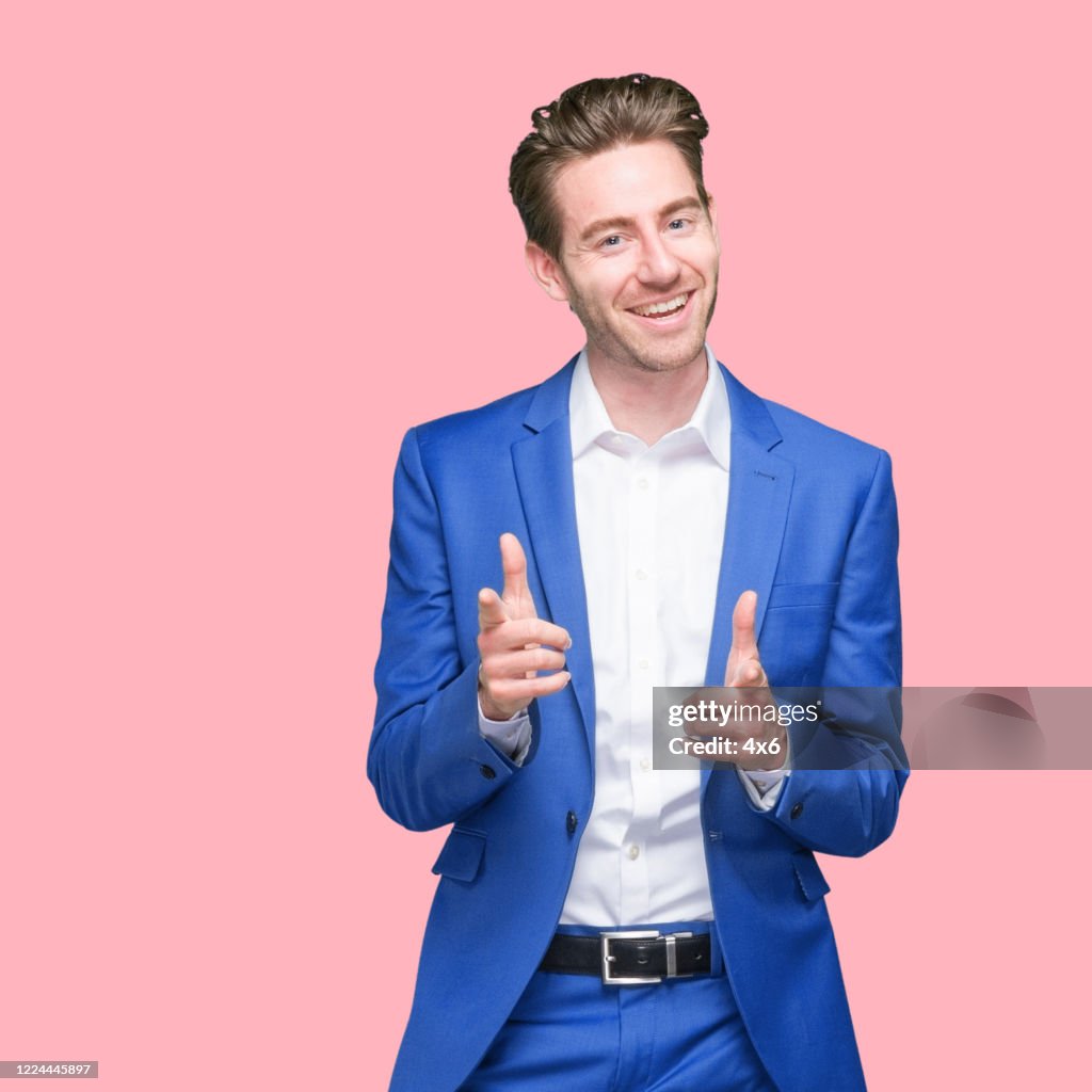 Caucasian young male businessman standing in front of colored background wearing button down shirt