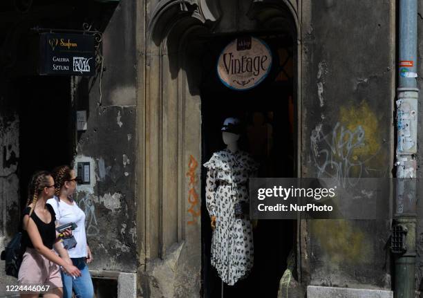 Two young ladies walk in front of a vintage shop in Krakow center. On July 02 in Krakow, Poland.