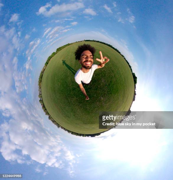 a portrait of a young man in the tiny planet format standing in the middle of a field smiling at the camera - 360 fotografías e imágenes de stock