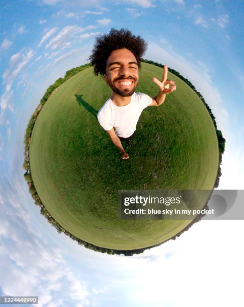 a portrait of a young man in the tiny planet format standing in the middle of a field smiling at the camera - 360 people stock-fotos und bilder