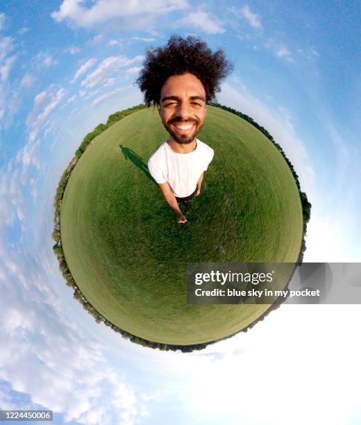 a portrait of a young man in the tiny planet format standing in the middle of a field smiling at the camera - 360 uk bildbanksfoton och bilder