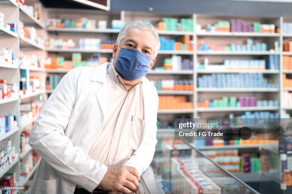 Portrait of male senior pharmacist with face mask at pharmacy