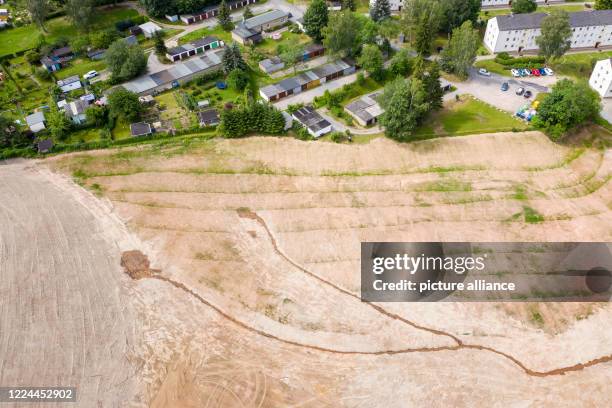 July 2020, Saxony, Bad Schlema: An excavator loads the symbolic last shovel to complete the rehabilitation of waste dump 65, while a truck transports...