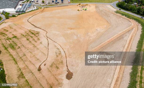 July 2020, Saxony, Bad Schlema: An excavator loads the symbolic last shovel to complete the rehabilitation of waste dump 65, while a truck transports...