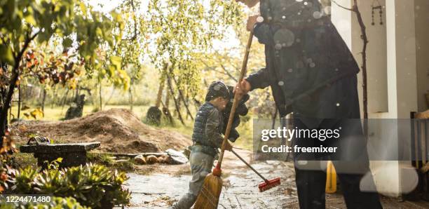 father and son sweeping water from front yard on rainy day - flood cleanup stock pictures, royalty-free photos & images