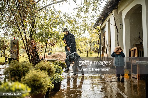 息子は雨の日に父を助け、前庭から水を掃く 息子は雨の日に父を助け、前庭から水を掃く