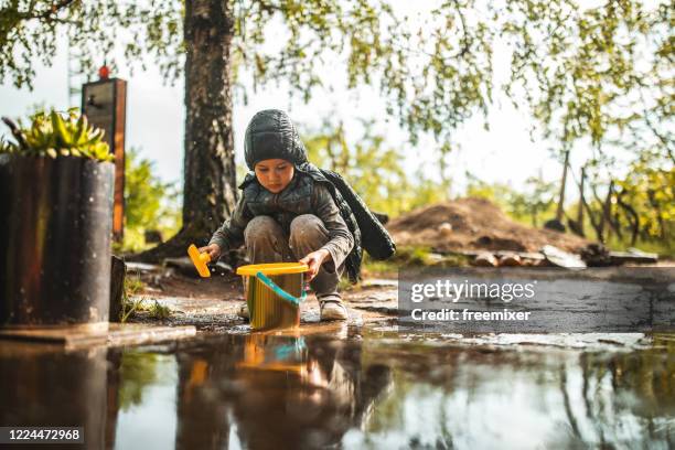 cute boy playing in back yard with bucket and shovel after rain - rain garden stock pictures, royalty-free photos & images