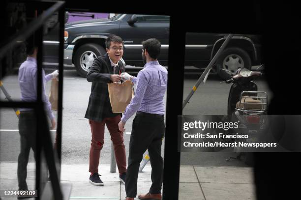 Stefan Fan picks up sourdough bread and miso soup from general manager Gregory Saavedra in front of Lazy Bear restaurant in the Mission on Thursday,...