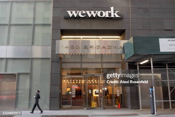 Woman wearing a mask walks near a WeWork office building amid the coronavirus pandemic on May 12, 2020 in New York City. COVID-19 has spread to most...