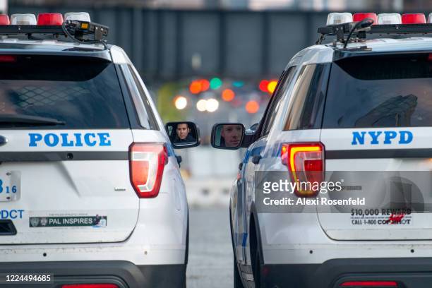 Two NYPD officers can be seen talking to each other through the reflection in their side-view mirrors near Hudson Yards amid the coronavirus pandemic...