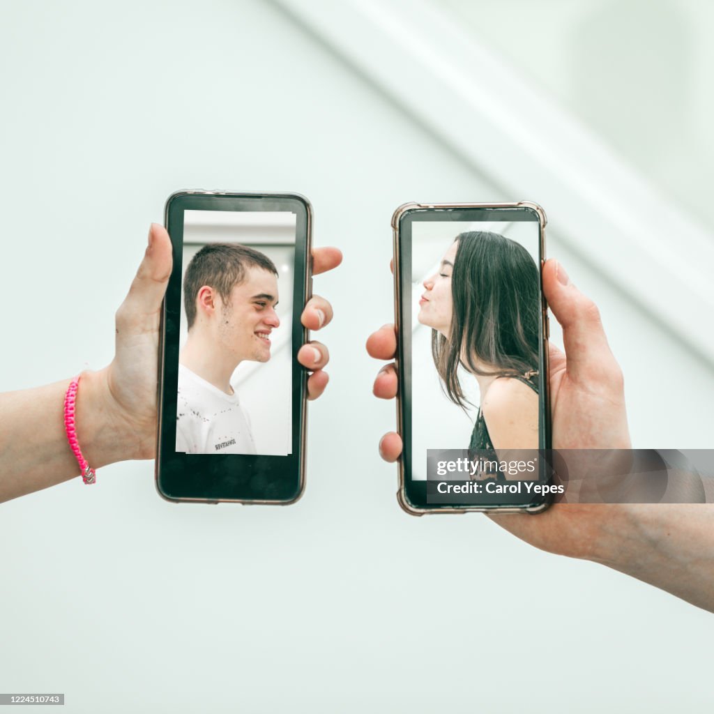 Millennial couple kissing via mobile devices