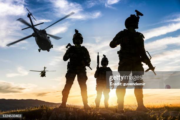 silhouettes of soldiers during military mission at sunset - armed forces stock pictures, royalty-free photos & images