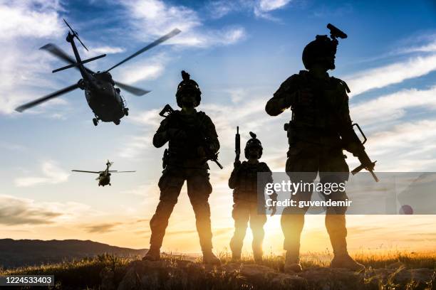 silhouettes of soldiers during military mission at sunset - militar imagens e fotografias de stock