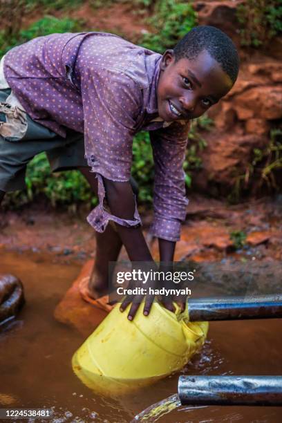 afrikanischer junge sammelt wasser aus dem brunnen, kenia, ostafrika - bohrloch stock-fotos und bilder