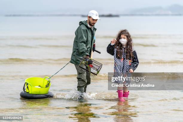 Little Claudia Basallo , niece of shellfisherman Adrián González , holds a clam caught by her uncle on May 12, 2020 in A Pobra do Caramiñal,...