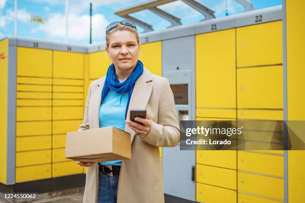 a woman wearing smart casual clothes at a package drop off point - picking up mail stock pictures, royalty-free photos & images