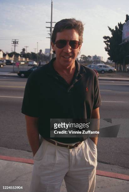 American actor and comedian Tim Allen wearing a Ralph Lauren polo shirt and white trousers, with his hands in the pockets, and sunglasses, as he...