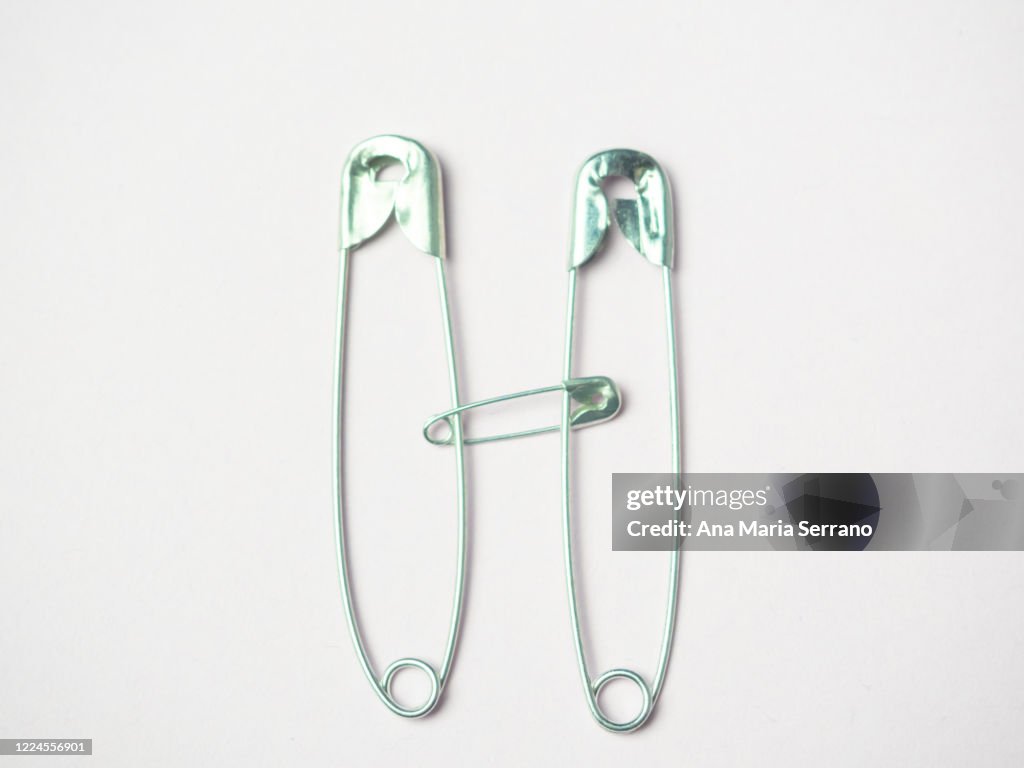 Hugging A Pin Sewing Safety Pins Representing Two People Hugging Photo - Getty Images