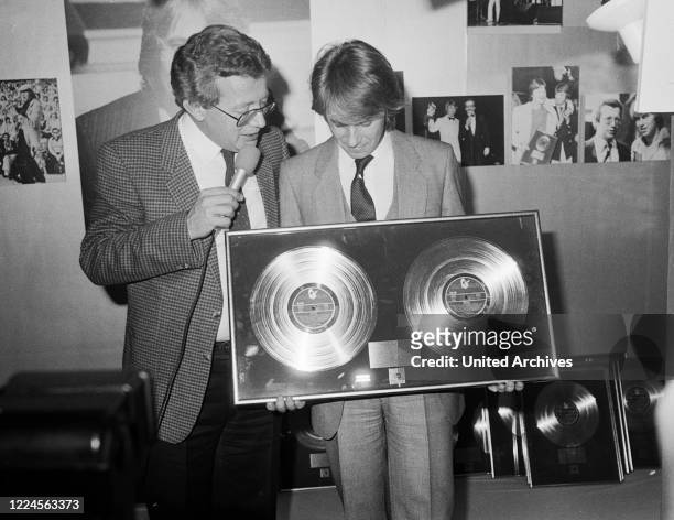 German schlager singer Roland Kaiser with Dieter Thomas Heck and golden disc at Hamburg, Germany circa 1978.