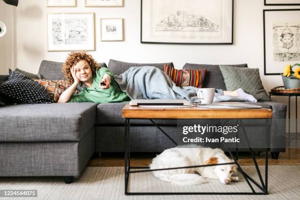 front view of a young redhead woman watching tv at home - woman watching tv stock pictures, royalty-free photos & images