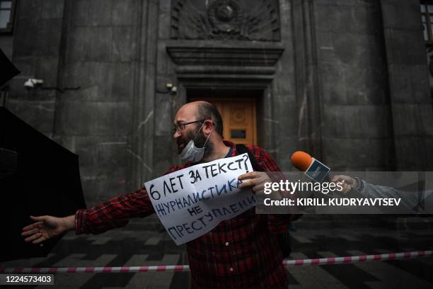 Russian journalist and activist Ilya Azar holds a banner reading "Journalism is not a crime" during a demonstration in support of journalist Svetlana...
