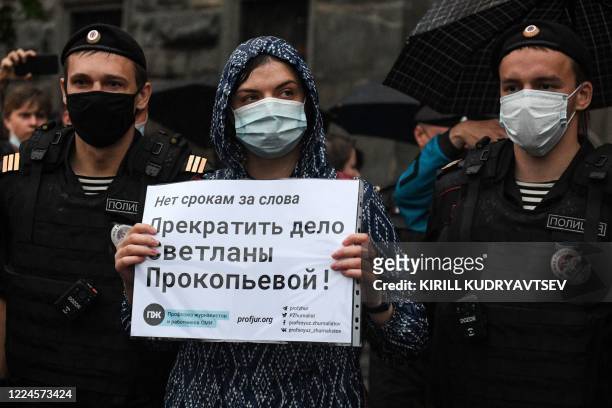Russian police officers detain an activist holding a banner reading "Stop the Svetlana Prokopyeva case" during a demonstration in support of...
