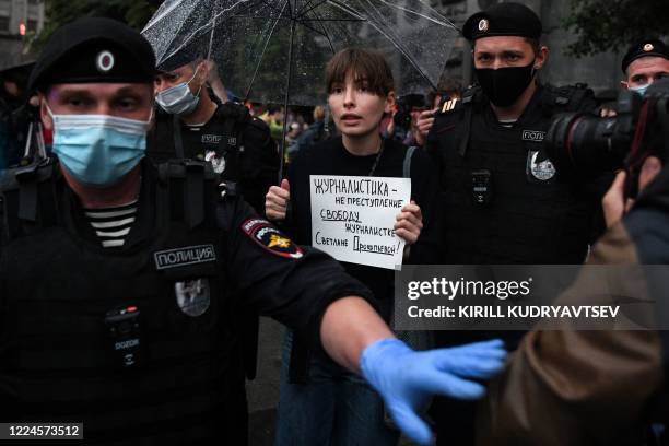 Russian police officers detain an activist holding a sign reading "Journalism is not a crime, Freedom for Svetlana" during a demonstration in support...