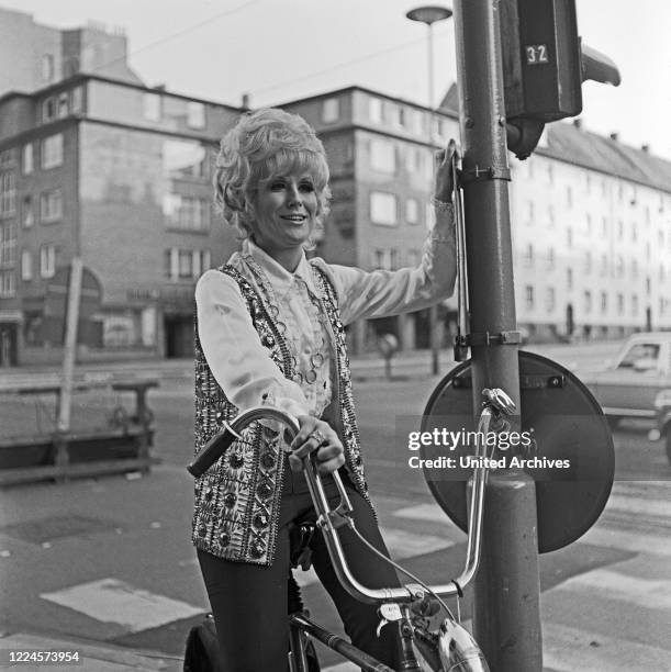 British pop and soul singer Dusty Springfield riding a bicycle while visiting Hamburg, Germany, 1970.