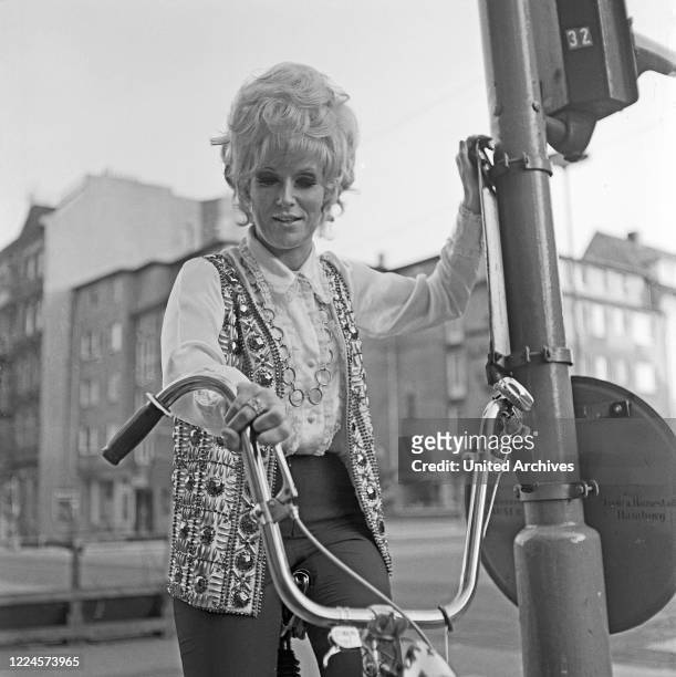 British pop and soul singer Dusty Springfield riding a bicycle while visiting Hamburg, Germany, 1970.