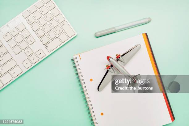 high angle view of computer keyboard, small airplane and note pad on turquoise background, planning and booking a flight on the internet - office small business stock-fotos und bilder