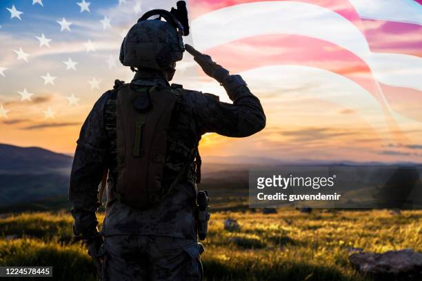 silhouette eines soliders, der bei sonnenaufgang gegen die us-flagge warnt - armed forces stock-fotos und bilder