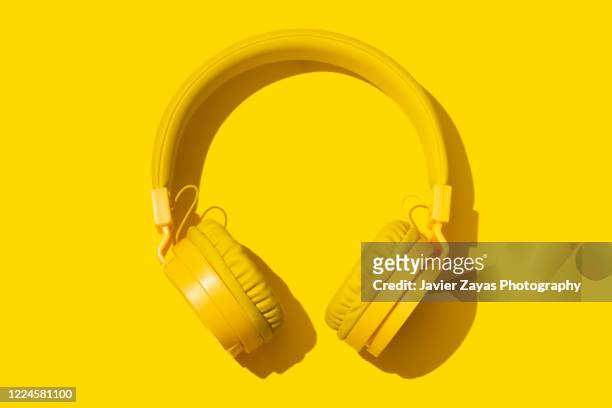 yellow headphones on a yellow background - yellow stock-fotos und bilder