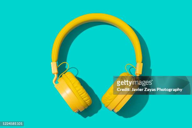 yellow headphones on a green background - musica pop foto e immagini stock