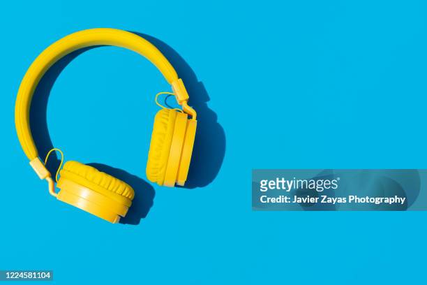 yellow headphones on a blue background - bluetooth speaker stock-fotos und bilder