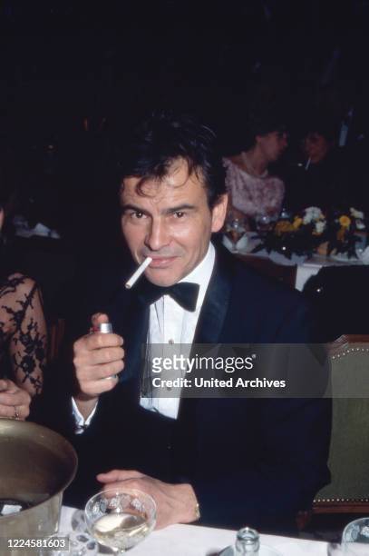 German actor Horst Buchholz lighting a cigarette, Germany, 1980s.