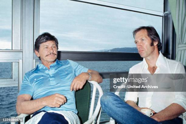 American actors Charles Bronson and David Carradine relaxing with a cup of coffee, Cannes Film Festival France, 1970s.