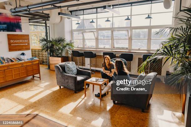 young women working in modern office space, sitting in lobby and discussing - lobby stock pictures, royalty-free photos & images