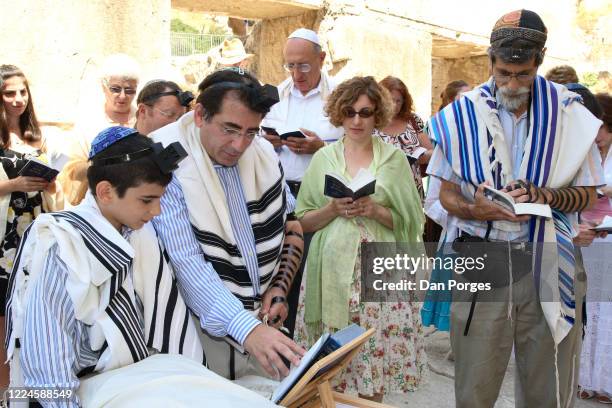 Bar Mitzva, a ceremony on a 13th birthday marking manhood for a Jewish boy, the boy reads from the Siddur with his father, mother and the Rabbi, men...