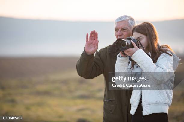 grandfather teaching granddaughter how to use a camera - senior photographer stock pictures, royalty-free photos & images