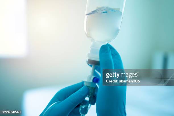 close up doctor wearing surgical gloves and use infusion for patient infected covid-19novel coronavirus(2019-ncov) - iv drip stock pictures, royalty-free photos & images