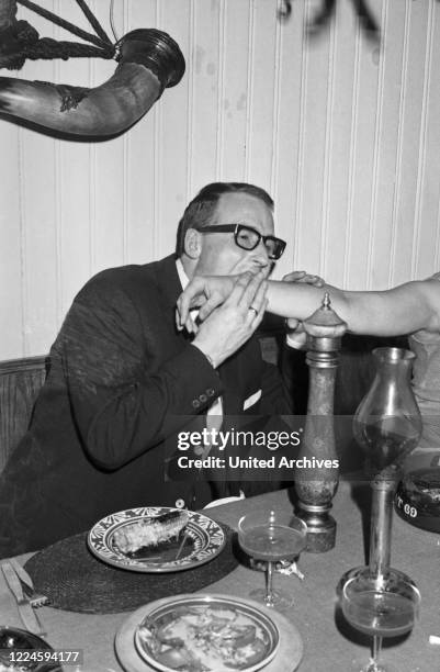 Austrian bassist, singer and producer Andy Fisher dining at a restaurant, Germany, 1960s.