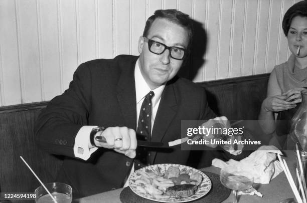 Austrian bassist, singer and producer Andy Fisher dining at a restaurant, Germany, 1960s.