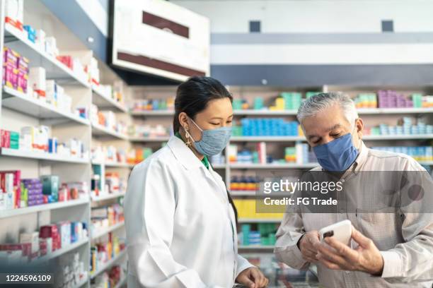 female pharmacist helping a senior customer - latin america covid stock pictures, royalty-free photos & images