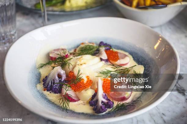 close-up view of cod fish covered with red caviar and vegetables on plate - nordic food stock-fotos und bilder