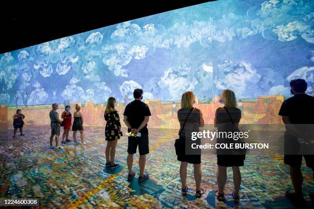 People are seen wearing masks as they experience an immersive Vincent Van Gogh art exhibit in Toronto, Ontario, Canada, on July 3, 2020. - Amid the...