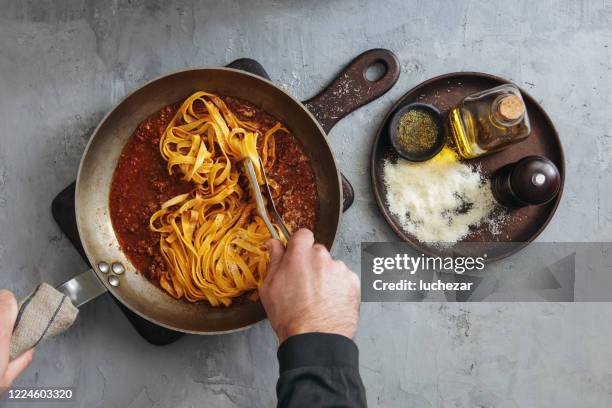 hombre cocina clásica tagliatelle con salsa boloñesa - salsa boloñesa fotografías e imágenes de stock