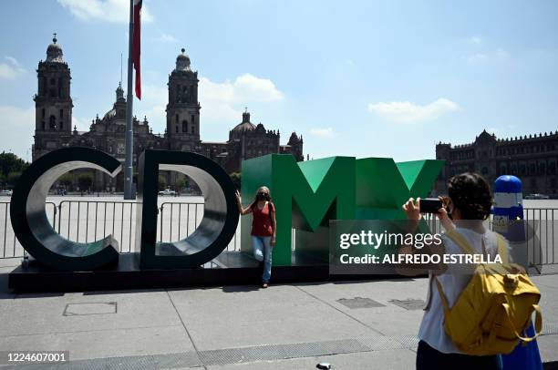 Tourist poses for a picture at the Zocalo square in Mexico City on July 3, 2020 as Mexico authorized the reopening of restaurants, shops, street...
