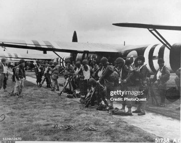 American troops from the 82nd Airborne Division check their equipment before the first airborne assault on the continent, England, June 6, 1944. A...